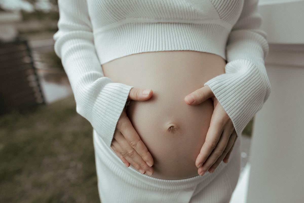 Femme enceinte en pull blanc tenant son ventre nu Femme enceinte en pull blanc tenant son ventre nu