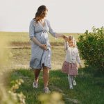 Une femme enceinte marche avec sa fille dans un champ verdoyant