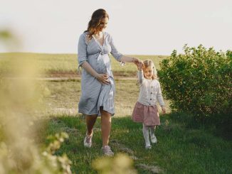 Une femme enceinte marche avec sa fille dans un champ verdoyant