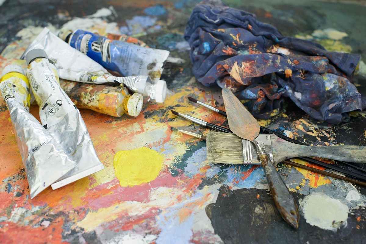 Palette d'artiste avec tubes de peinture, pinceaux, couteau à palette, chiffon taché Palette d'artiste avec tubes de peinture, pinceaux, couteau à palette, chiffon taché