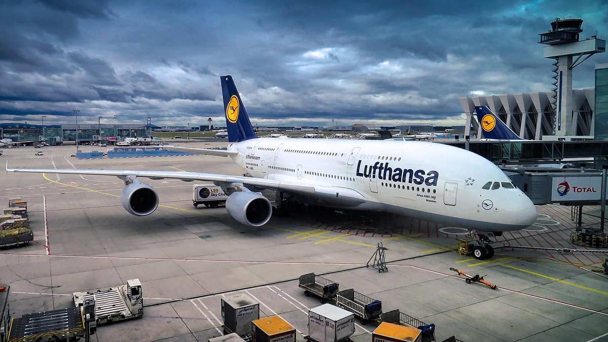 Avion Lufthansa blanc et bleu immobilisé à la porte d'embarquement d'un aéroport Avion Lufthansa blanc et bleu immobilisé à la porte d'embarquement d'un aéroport