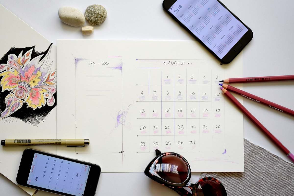Planification d'août sur papier avec smartphone, crayons et accessoires Planification d'août sur papier avec smartphone, crayons et accessoires